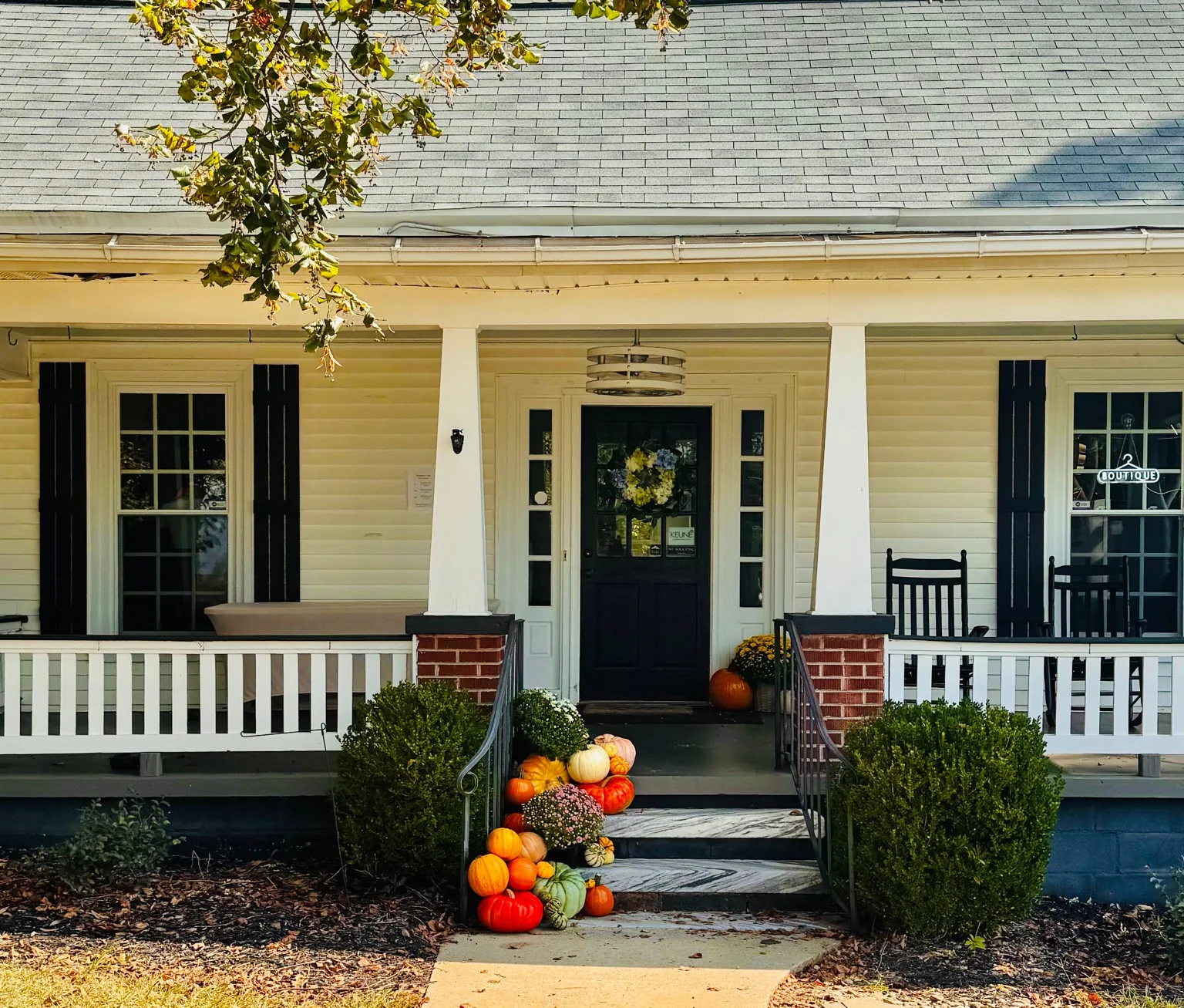 Pumpkins, gourds and potted mums lining the steps of a white porch